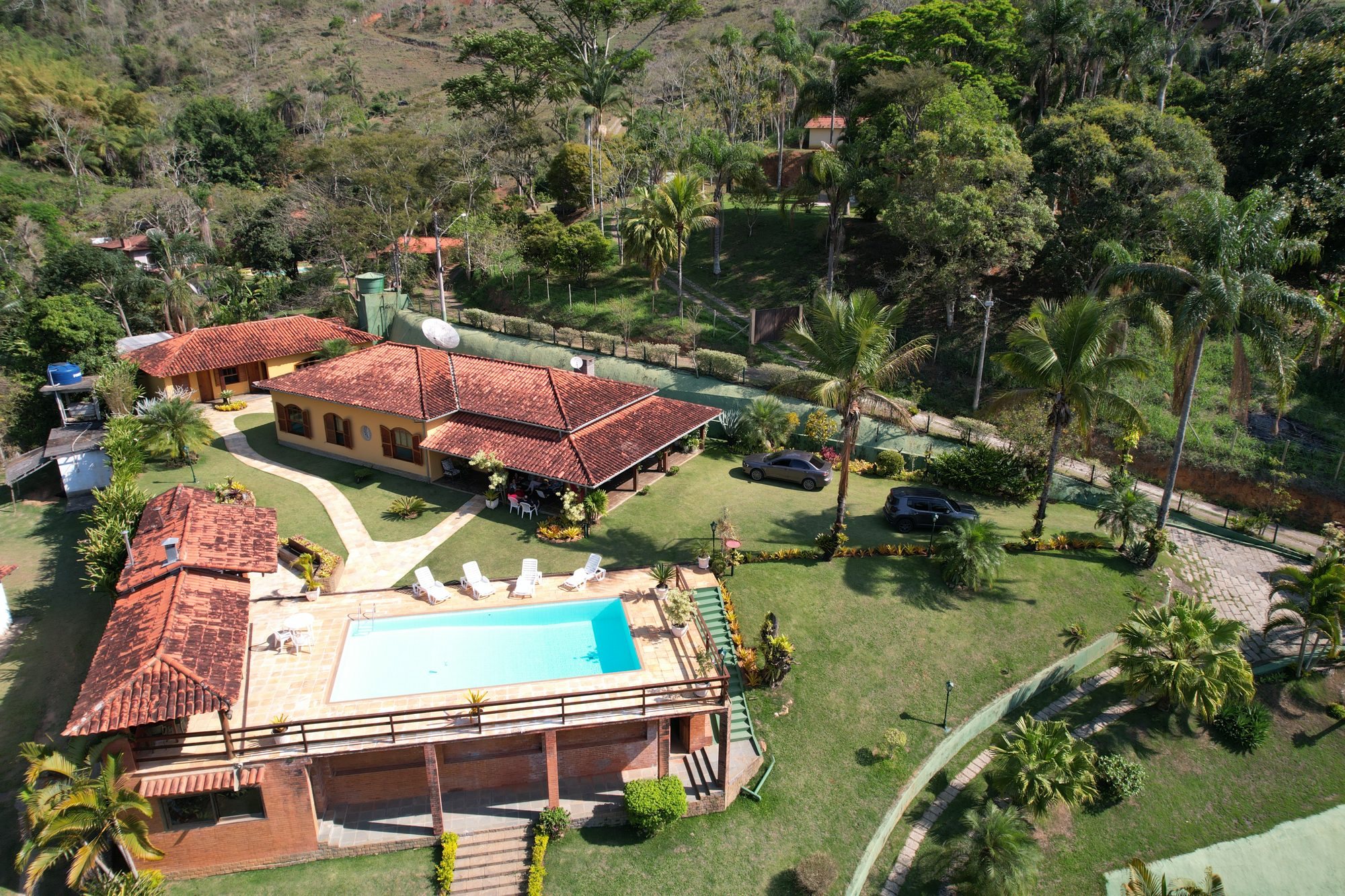 Vista aérea da casa com piscina e jardim cercados pela mata em Fagundes, Petrópolis
